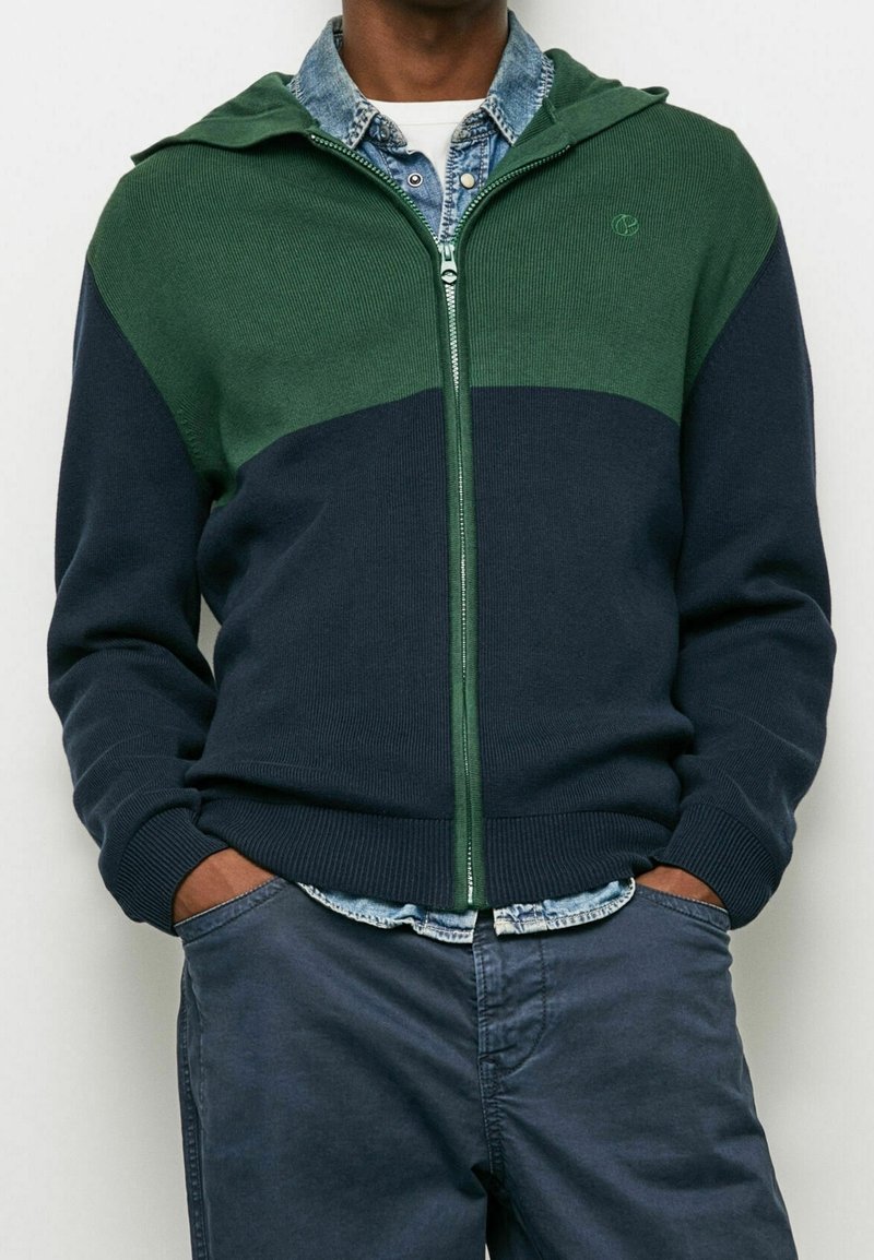 Grön och marinblå zip-up hoodie i ribbat tyg. Har en huva, kontrasterande färger och en logotypdetalj på bröstet.