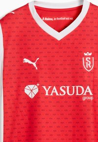 Czerwona koszulka piłkarska z białym kołnierzykiem, powtarzający się wzór koron, logo Puma, oznaczenie SR oraz sponsor Yasuda Group z przodu.
