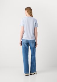 Lys blå bomull T-skjorte med rund hals, korte ermer, sammen med høy midje, vide blå denim bukser. Enkelt design, minimale detaljer.