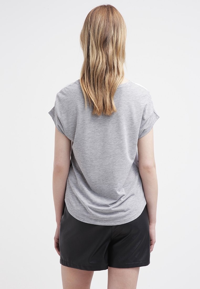Grå kortærmet t-shirt med løs pasform, der har en rund kant og blødt stof, parret med sorte shorts.