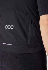 Maillot de cyclisme noir avec poche zippée, texture subtile et logo "poc" brodé. Manches courtes et coupe ajustée pour la performance.