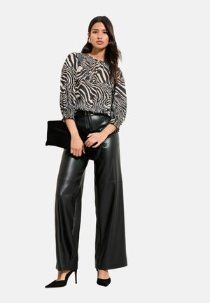 Black and beige zebra-print blouse with puffed sleeves, paired with high-waisted black leather wide-leg pants and black high heels.