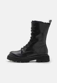 Bottine en cuir noir à lacets, avec une semelle en caoutchouc noir épaisse et une doublure en fourrure texturée sur le haut.