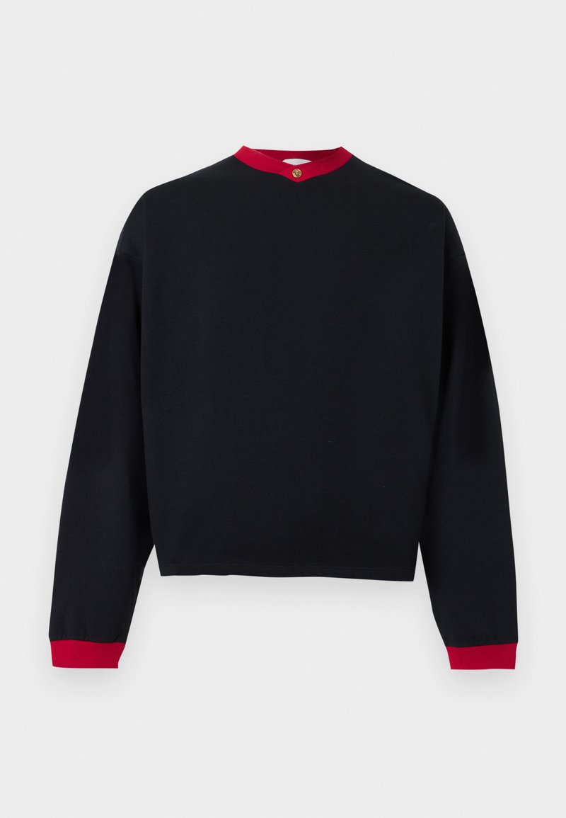 Chemise noire à manches longues avec col et poignets rouges, ornée d'un petit bouton doré à l'encolure, présentée sur fond blanc.