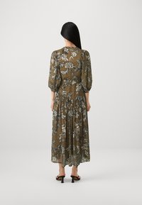 Floral maxi dress in olive green with puffed sleeves, sheer fabric, and a tiered design. Features white and blue floral patterns.