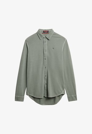 Camisa de manga larga verde claro con cuello puntiagudo, cierre frontal de botones, dobladillo curvado y pequeño logotipo en el pecho. Textura de tela suave.