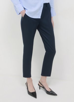 Pantalon marine ajusté à coupe slim et texture lisse, associé à des escarpins noirs à bride arrière pointus. Design classique pour un port polyvalent.