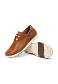 Scarpe stringate in pelle marrone con un design cucito, suola in gomma tessurizzata color tan e crema, e dettagli minimi. Presentano una punta rotonda e una finitura morbida.