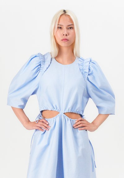 Rochie bleu deschis cu mâneci bufante, detalii franjurate și tăieturi laterale. Materialul pare neted, având o croială lejeră și șnururi ajustabile.
