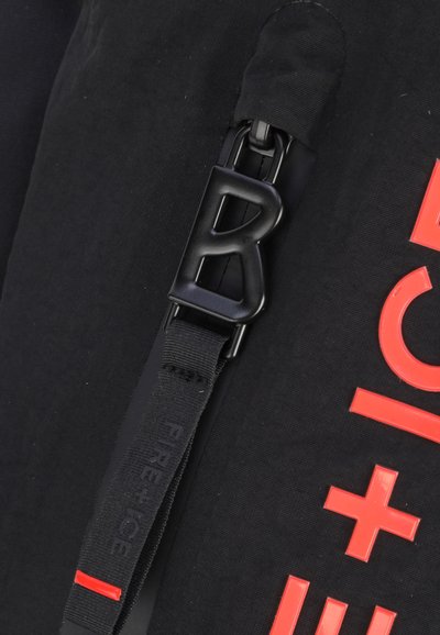 Schwarzer Stoff mit strukturierter Oberfläche, mit einer auffälligen schwarzen Schnalle in Form des Buchstabens "R". Heller roter Drucktext liest "FIRE + ICE."