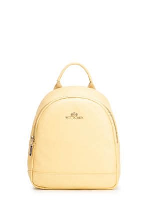Pequeña mochila de cuero amarillo pálido con asa superior, bolsillo frontal con cremallera y logo "Wittchen" en letras doradas.