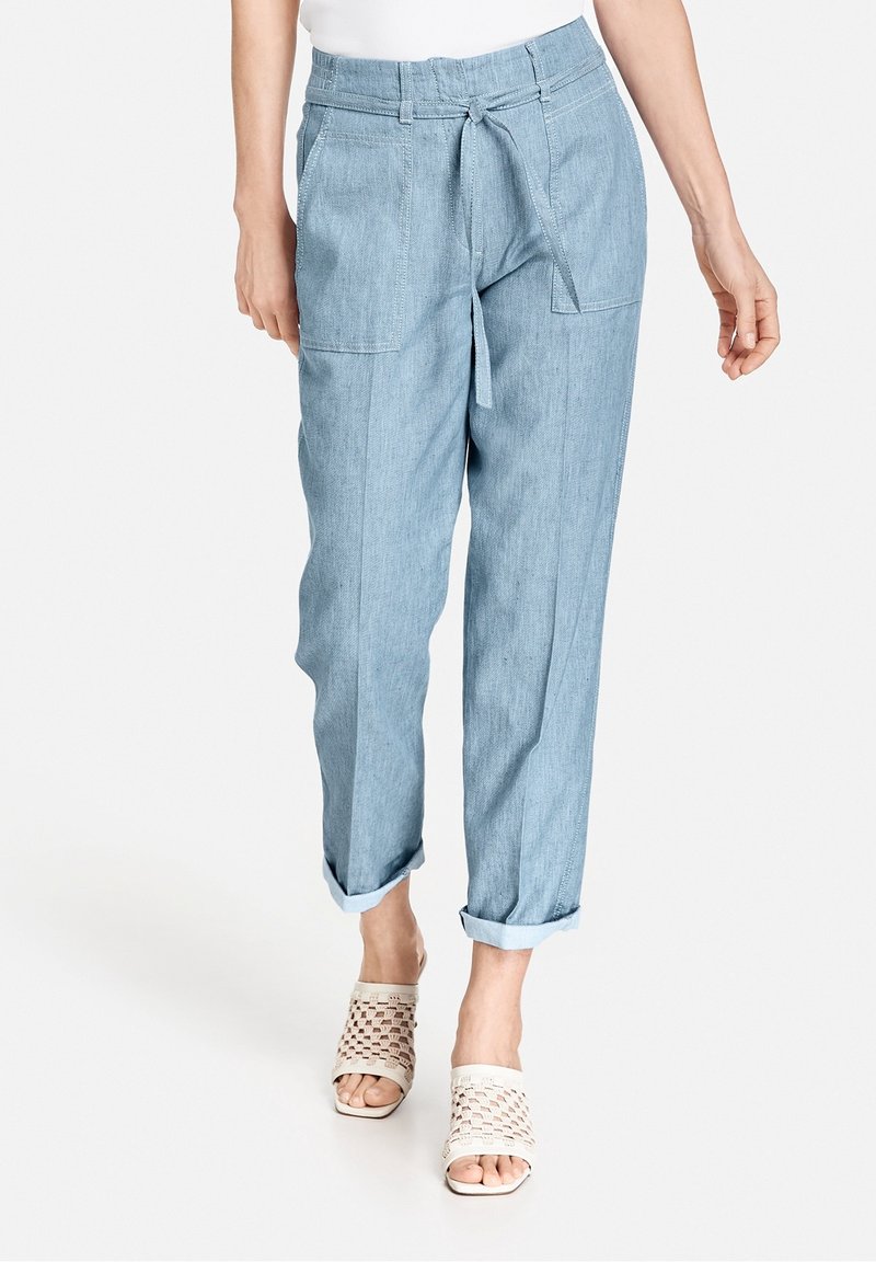 Jasnoniebieskie spodnie o luźnym kroju, wykonane z tkaniny przypominającej dżins, z elastycznym pasem na sznurku, podwiniętymi mankietami i kieszeniami bocznymi.