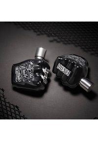 Bouteilles de parfum en forme de poing noir avec des accents argentés ; l'une présente une écriture blanche, l'autre a "DIESEL" gravé sur la base, texture brillante.