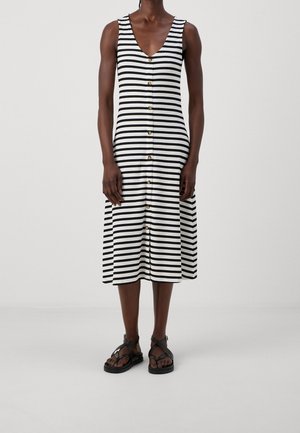 Midi sukienka w paski w czarno-białym kolorze, dzianina prążkowana, dekolt w serek, guziki z przodu, zestawiona z czarnymi sandałami.