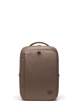 Sac à dos marron rectangulaire avec poignée supérieure, poche avant zippée et petite étiquette de marque dans le coin inférieur droit sur fond blanc.
