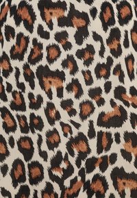 Tessuto a stampa leopardata con macchie nere e marroni su uno sfondo crema. La trama è liscia con motivi distinti e irregolari.