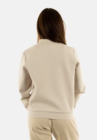 Felpa beige con colletto a coste, vestibilità comoda e texture liscia. Il capo presenta maniche lunghe e orlo dritto.
