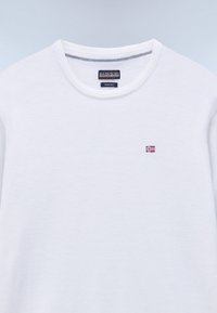 Maglione in lana merino bianca con collo rotondo, piccolo emblema della bandiera norvegese sul petto e etichetta del marchio Napapijri all'interno del colletto.