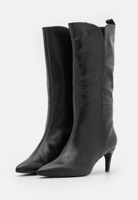 Botas de cuero negro hasta la rodilla con un acabado suave, punta afilada y un panel de tela texturizada, que cuentan con un tacón de aguja de 5 cm.