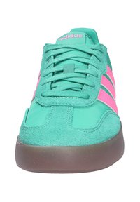 Tirkizne Adidas tenisice s ružičastim prugama, usklađeni ružičasti logo na jeziku, teksturirani materijal i smeđa sola, pogled sprijeda.