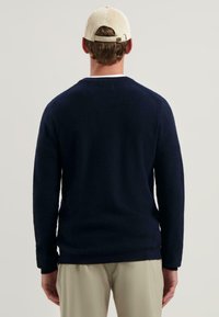 Marineblaues Strickpullover mit Rundhalsausschnitt und gerippten Bündchen. Hergestellt aus weichem Stoff, mit einem strukturierten Muster und einer lässigen Passform.