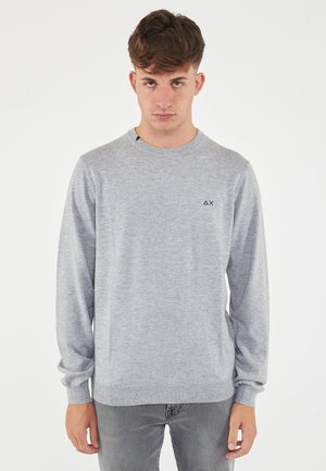 Maglione grigio realizzato in tessuto a maglia morbido, dotato di scollatura rotonda, maniche lunghe e un piccolo logo sul petto. Vestibilità casual.