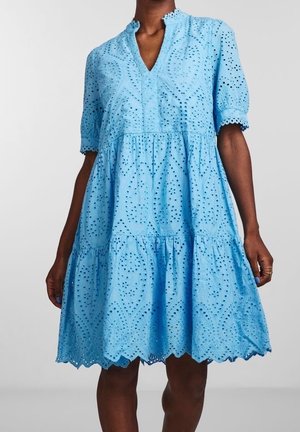 Light blue knee-length dress with eyelet lace patterns, short sleeves, and scalloped hem worn by a standing person.