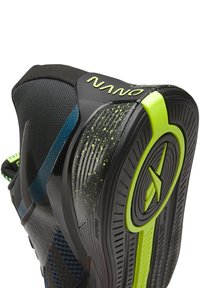 Shoe desportivo preto com parte superior texturizada, detalhes vibrantes em azul e sola neon verde contrastante com acabamento salpicado.