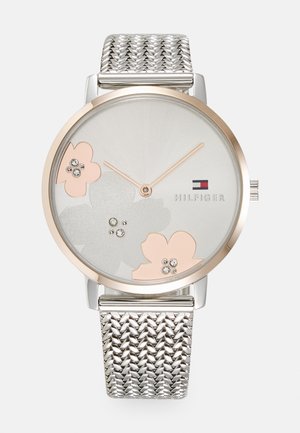 Silver mesh strap watch with a round gold-tone case, silver dial featuring floral designs in pink and gray, and crystal accents.
