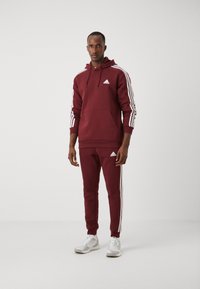 adidas Sportswear ESSENTIALS TAPERED CUFF 3-STRIPES  - Treniņtērpa apakšdaļas - shadow red