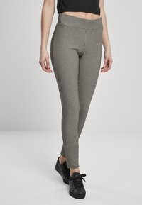 Leggings a cuadros en blanco y negro, hechas de una tela elástica con una cintura alta, combinados con zapatillas negras. Textura suave con diseño ajustado.