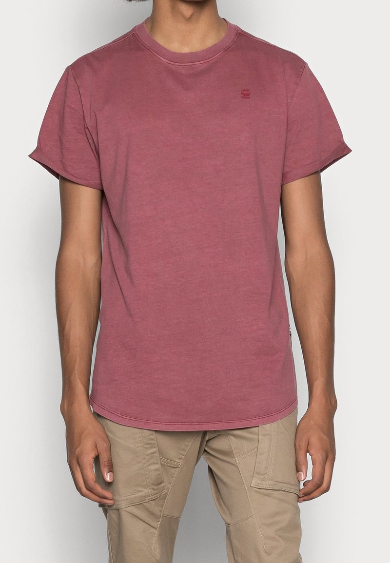 T-shirt bordeaux avec un col rond, des manches courtes et un logo sur la poitrine. Fabriqué en tissu léger, texture lisse.