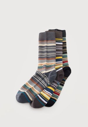 Trois paires de chaussettes mi-mollet à rayures horizontales colorées, avec des pointes et des talons contrastés, disposées sur un fond clair.
