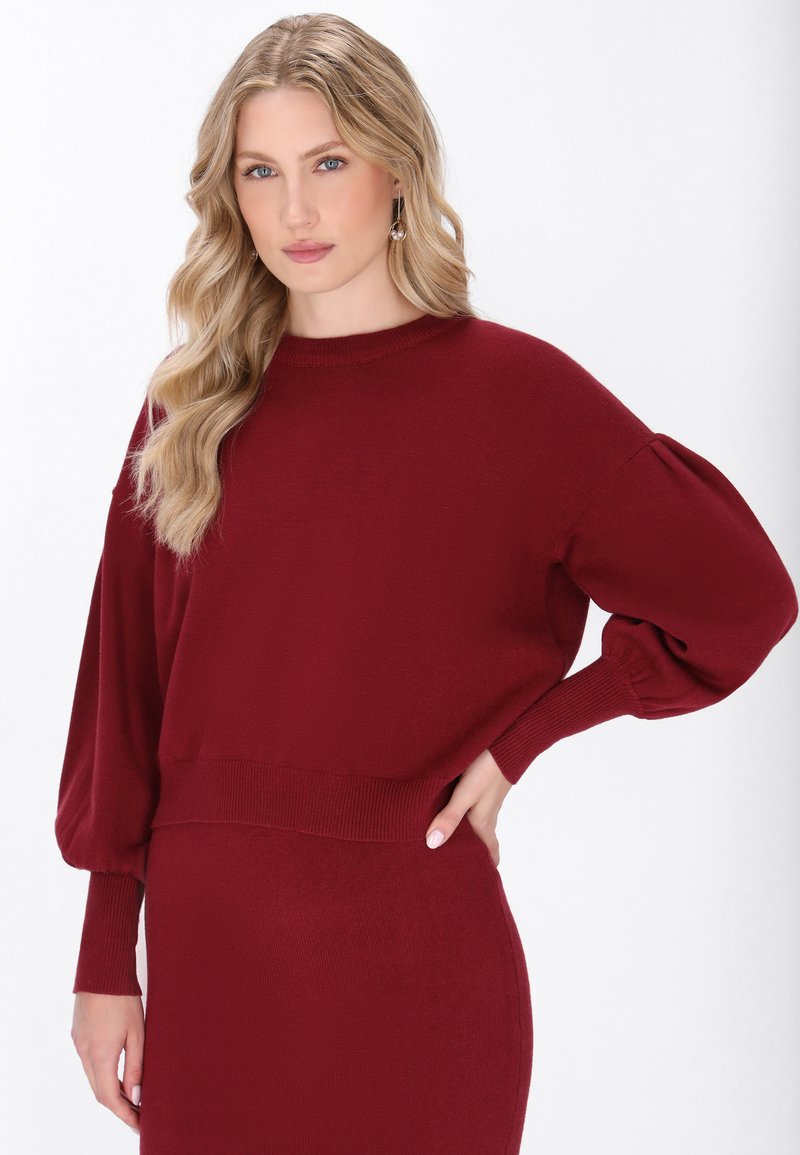 Burgunderfarbener Strickpullover mit kastigem Schnitt, senkten Schultern und gerippten Bündchen. Weiche Textur mit einem einfachen, klaren Design.
