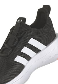 Černá sportovní bota s síťovinovým svrškem, která má tři bílé pruhy, černé tkaničky a bílou polstrovanou podrážku označenou "cloudfoam."