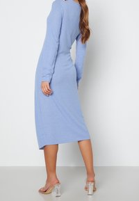 Robe à manches longues côtelée de couleur bleu clair, au design ajusté, de longueur midi, avec une texture lisse et une ouverture discrète dans le dos.