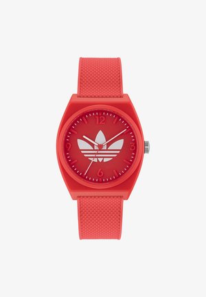 Montre-bracelet rouge avec bracelet texturé, cadran rouge affichant le logo blanc Adidas et trois aiguilles argentées indiquant l'heure.