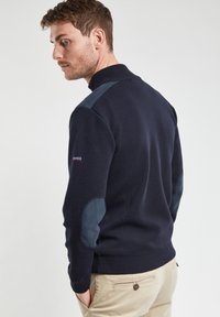 Pull en tricot bleu marine avec un col haut, doté de coudières bleu foncé et d'une finition texturée. Fabriqué à partir d'un matériau doux et durable.