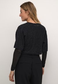 Black cropped sweater made of textured fabric with subtle metallic threads, featuring short sleeves and a rounded neckline.