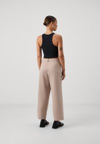 Svart ribbad linne topp i kombination med ljusbeige vida byxor. Outfitet har en elegant design, och svarta klackskor med blockklack.