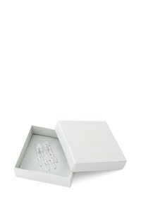 Pendientes de plata exhibidos en una caja texturizada de un gris claro con embossing dorado. Los pendientes presentan cadenas colgantes con acentos de cristal circular.