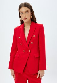 Rode dubbelzijdige blazer met gouden knopen, metgezelle kraag en voorzakken. Gladde stof met een getailleerde pasvorm en gestructureerd design.