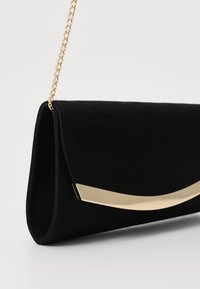 Mustmust clutch kuld metallist kaareva aktsendiga ja kettrihmaga. Disainil on sleek ja minimalistik kuju.