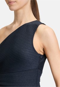 Asymetryczna sukienka na jedno ramię w ciemnoniebieskim kolorze z pionowym prążkowanym wzorem. Posiada dyskretny zamek błyskawiczny z boku oraz subtelny blask w tkaninie.