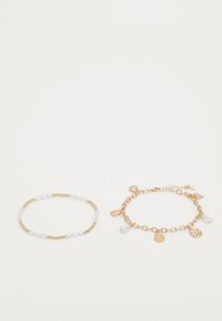 Gold-tone chain bracelet with charms, and a beaded bracelet featuring gold and clear beads. Textured design, with hanging accents.