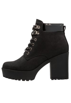 Black suede ankle boots with a chunky high heel, featuring silver hardware, round laces, and a glossy black accent at the ankle.