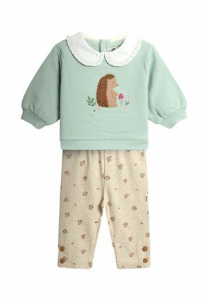 Haut bébé manches longues vert clair avec col à volants blanc et broderie de hérisson, associé à un legging beige à fleurs avec détails de boutons.