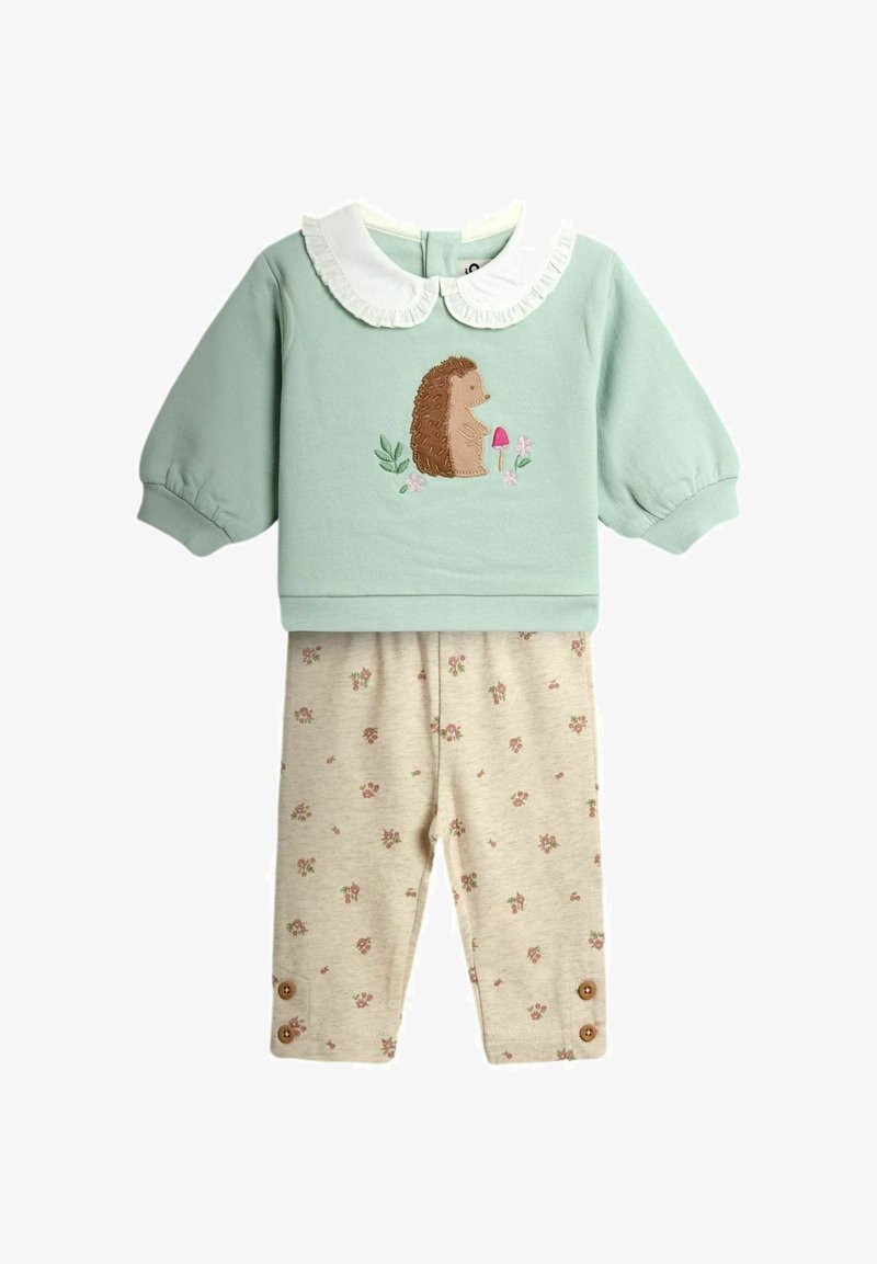 Bluza verde deschis pentru bebeluși cu mâneci lungi, guler plisat alb și broderie cu arici, asortată cu colanți bej cu model floral și detalii cu nasturi.