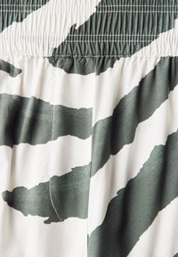 Katoenen shorts met een elastische tailleband, met een witte achtergrond en een gedurfde donkergroene tijgerstreep patroon. Glad textuur met nette stiksels.