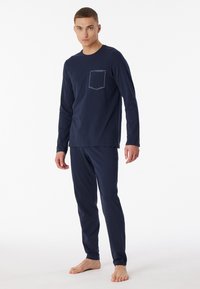 Navyblaues Baumwolle-Loungewear-Set mit langen Ärmeln, einer Brusttasche und schmal geschnittenen Hosen mit glatter Textur.